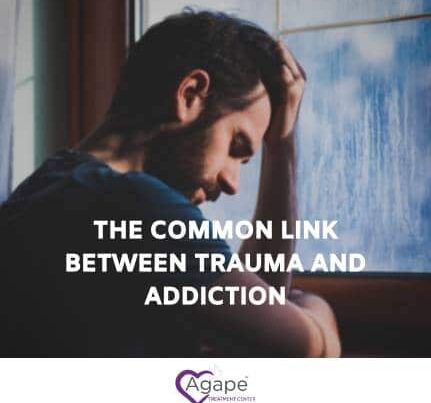 Person sitting by window, holding head in hands, with text The Common Link Between Trauma and Addiction.