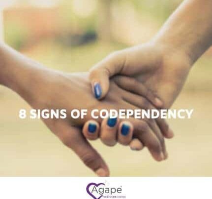 Two hands holding with blue nail polish and 8 Signs of Codependency text.