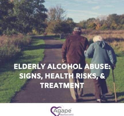 Elderly couple walking on a path surrounded by trees, wearing jackets.