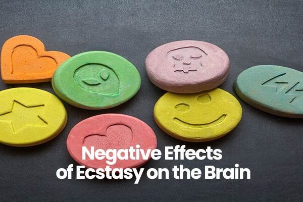 Colorful tablets with various icon imprints and text Negative Effects of Ecstasy on the Brain on a dark surface.