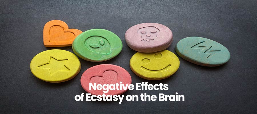 Colorful tablets with various icon imprints and text Negative Effects of Ecstasy on the Brain on a dark surface.