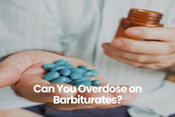 Person holding blue pills and brown bottle.