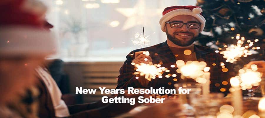 Person wearing Santa hat holding sparkler, text overlay New Years Resolution for Getting Sober.