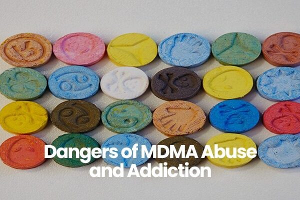 Colorful tablets with various embossed symbols above text Dangers of MDMA Abuse and Addiction.