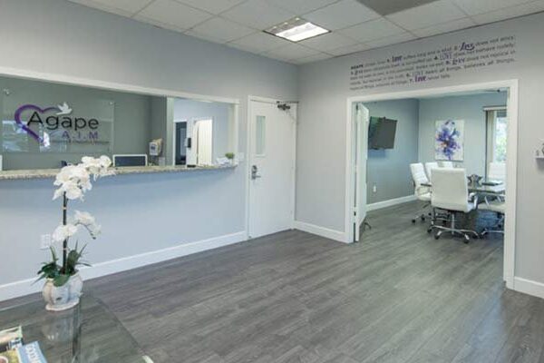 Reception area with plants, wall decoration, and Agape Rehab sign with purple heart.