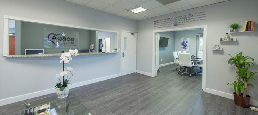 Reception area with plants, wall decoration, and Agape Rehab sign with purple heart.
