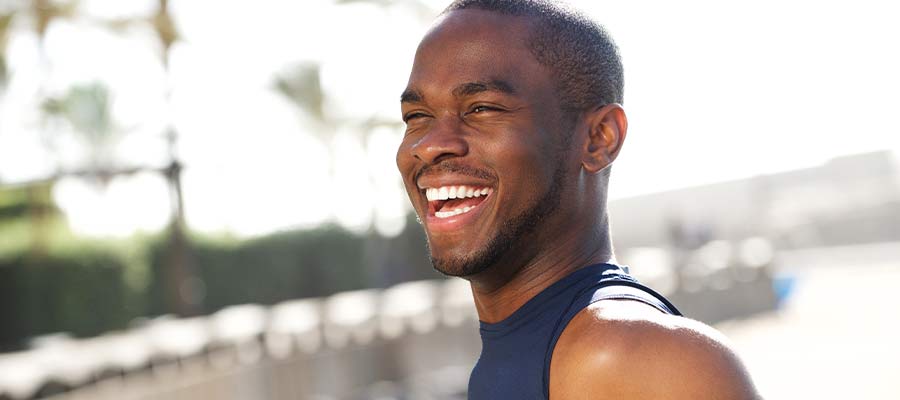 Person wearing a sleeveless shirt and smiling outdoors.