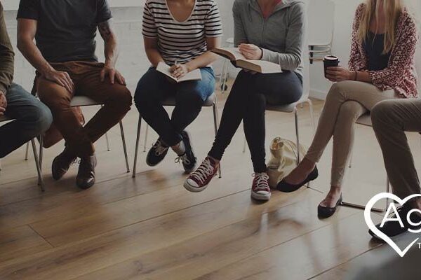 People sitting in a circle with Agape Treatment Center logo in the corner.