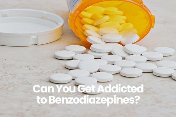 Prescription bottle with white pills spilled, lid nearby, text Can You Get Addicted to Benzodiazepines?