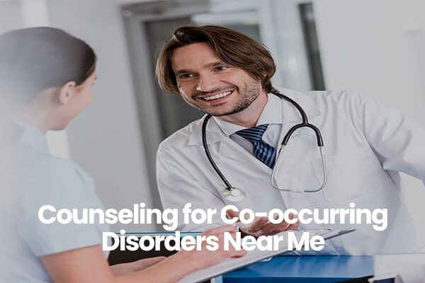 Person in white coat with stethoscope smiling and talking to another person.