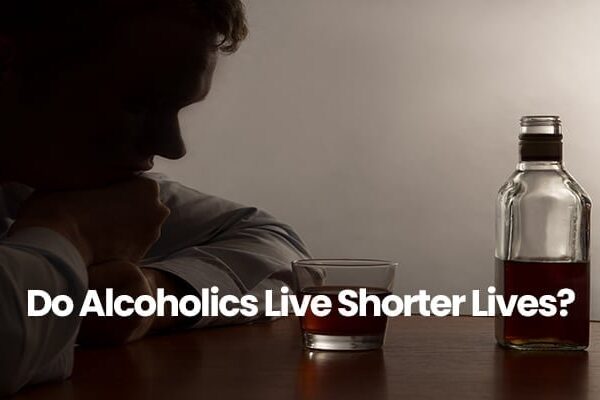 Silhouette of a person sitting at table with a bottle and glass of alcohol.