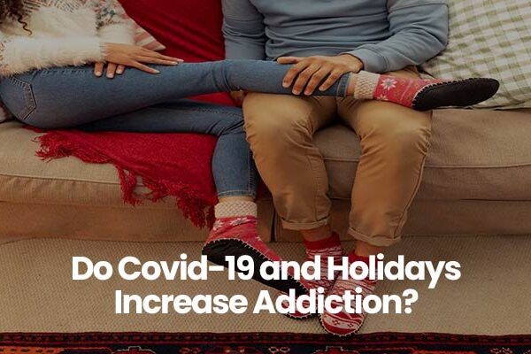 Two people sitting on a couch, wearing festive sweaters and socks, question about Covid-19 and holidays.