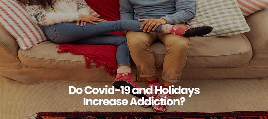 Two people sitting on a couch, wearing festive sweaters and socks, question about Covid-19 and holidays.