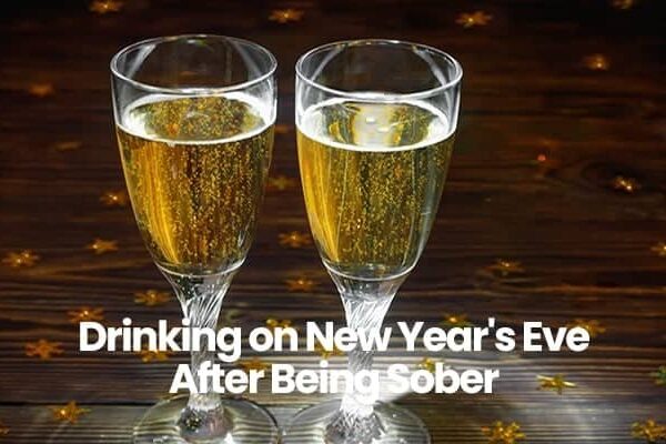 Two champagne glasses on wooden table with New Year's Eve text.