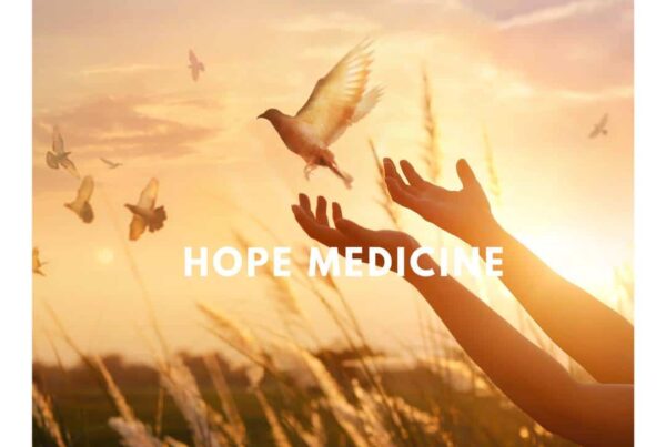 Silhouette of hands releasing a bird with text HOPE MEDICINE at sunset.