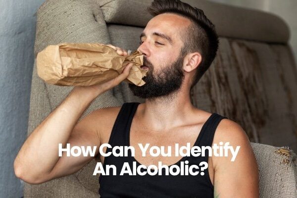 Person in black tank top sitting on sofa drinking from paper bag.