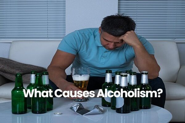 Person in blue shirt sitting with head down, surrounded by beer bottles.
