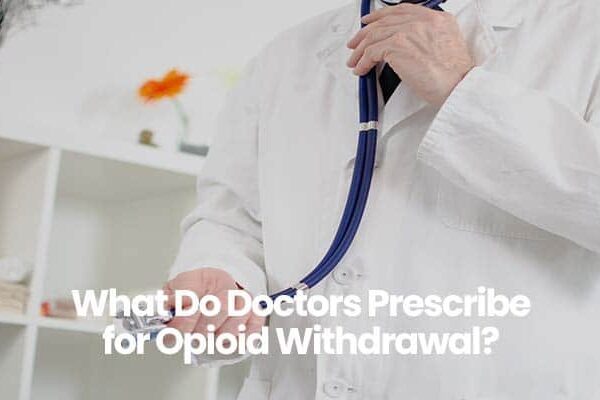Doctor in white coat holding stethoscope with medical shelves in background.