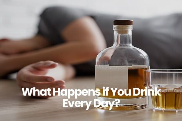 Person lying on floor near bottle and glass of alcohol.