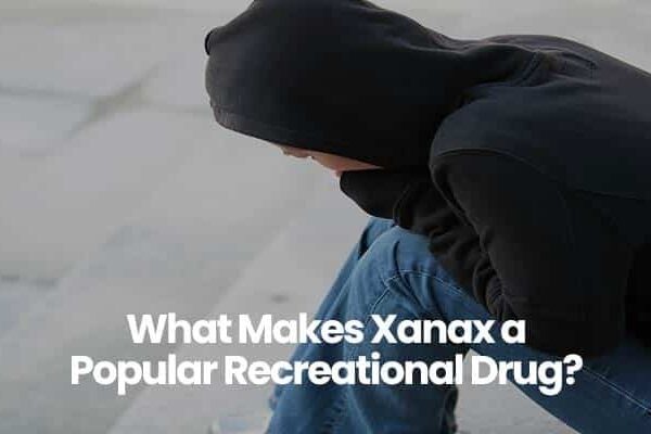 Person in black hoodie sitting with text: What Makes Xanax a Popular Recreational Drug?