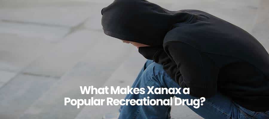 Person in black hoodie sitting with text: What Makes Xanax a Popular Recreational Drug?