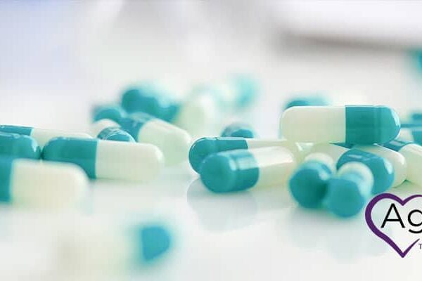 Scattered blue and white capsules with Agape heart logo on the side.