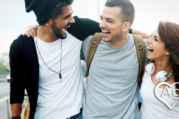 People smiling and embracing on a bridge, with Agape Treatment Center logo.