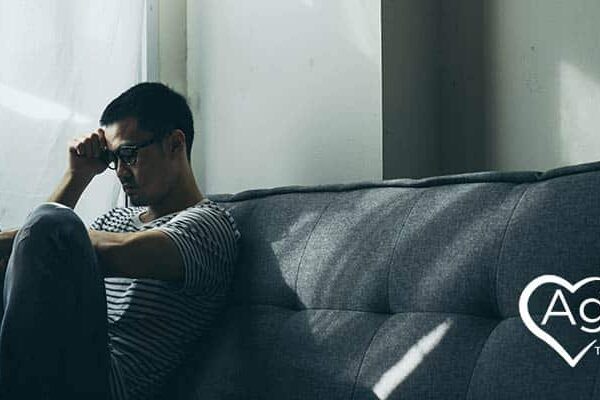 Person sitting on sofa wearing striped shirt looking thoughtful.
