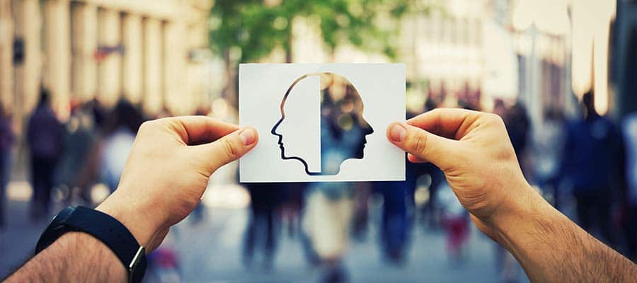 Silhouette of two heads on paper held by hands in a blurred city street.