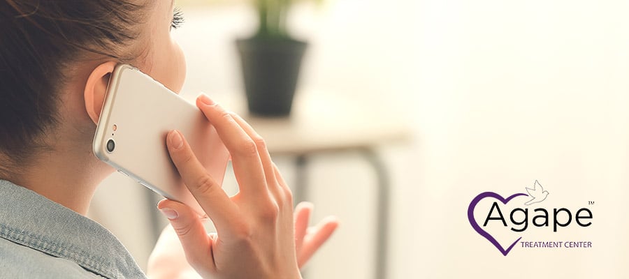 Person in denim holding phone to ear.