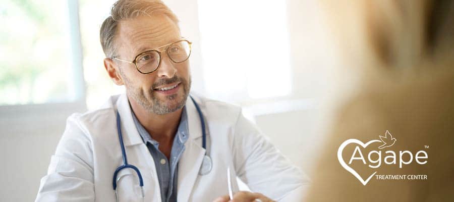 Person in white lab coat with stethoscope, listening attentively.
