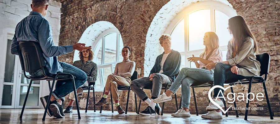 People sitting in a circle having a discussion, one person gestures while speaking.