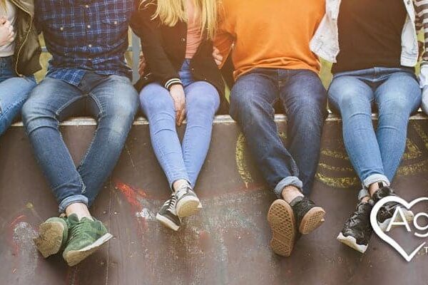 People sitting on a wall wearing casual clothes, logo with heart and Agape Treatment Center.