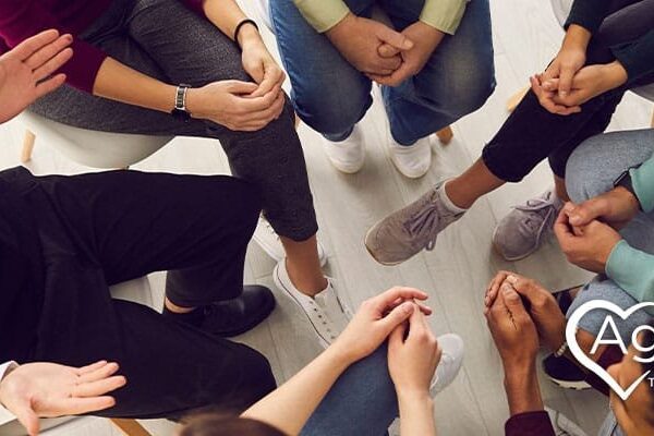 People sitting in a circle, hands visible, with the Agape Treatment Center logo in the corner.