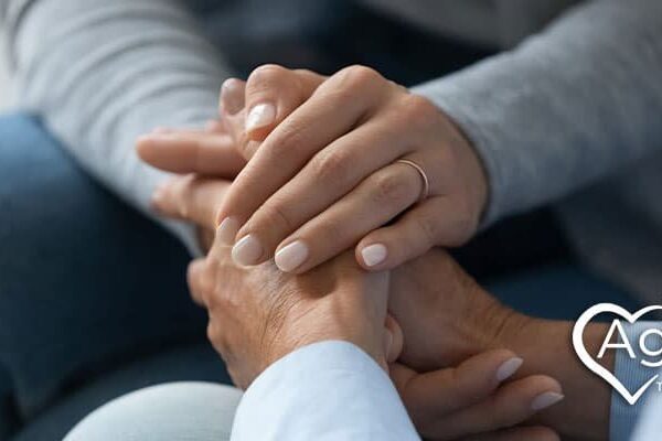 Hands offering comfort with Agape Treatment Center logo in white heart shape.