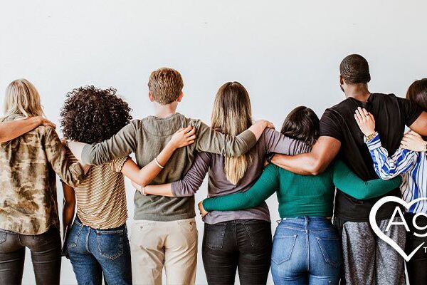 Group of people standing with arms linked, facing away.