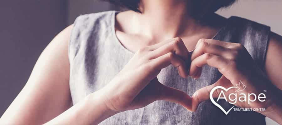 woman holding up her hands in the shape of a heart to represent gratitude