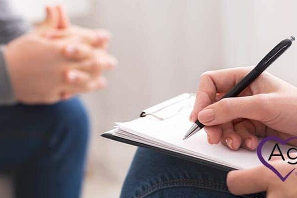 Person holding pen and clipboard, logo of Agape Treatment Center visible.
