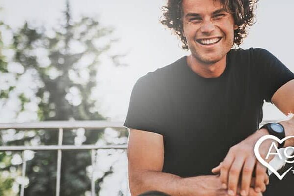 Person in black shirt smiling, Agape Treatment Center logo.