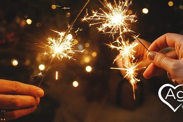 People holding sparklers with Agape Treatment Center logo visible.