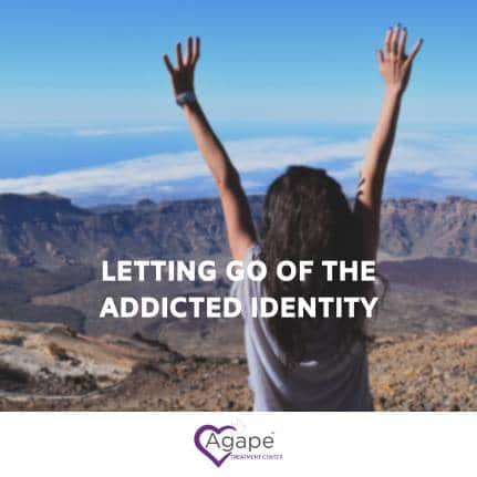 Person raising arms in front of mountain landscape with text LETTING GO OF THE ADDICTED IDENTITY.
