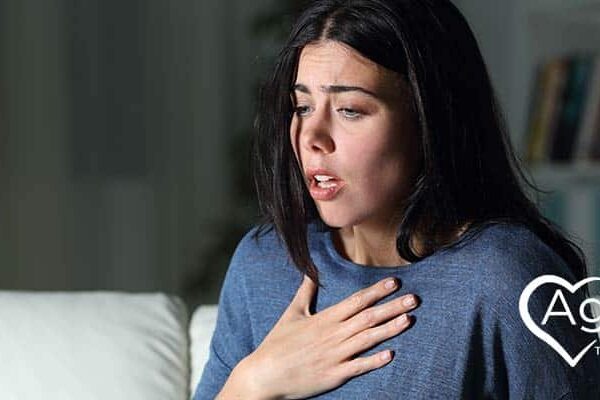 Person in blue sweater holding chest with distressed expression.