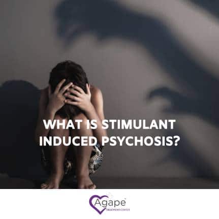 Person sitting, head in hands, with shadowy figures on wall. Text: What is stimulant induced psychosis?