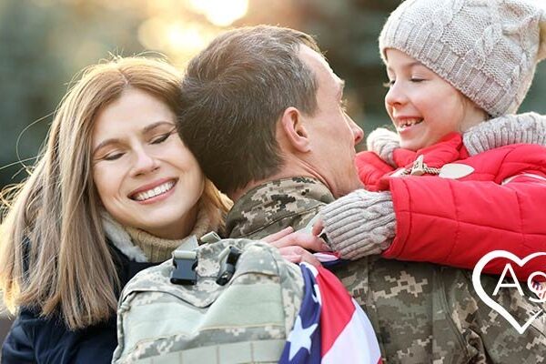 Family hugging soldier in camouflage uniform, woman smiling, child in red coat and knit hat.