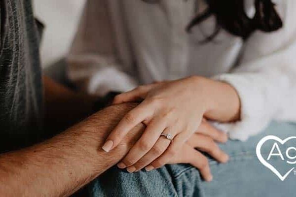 Person holding hands, wearing a white shirt.