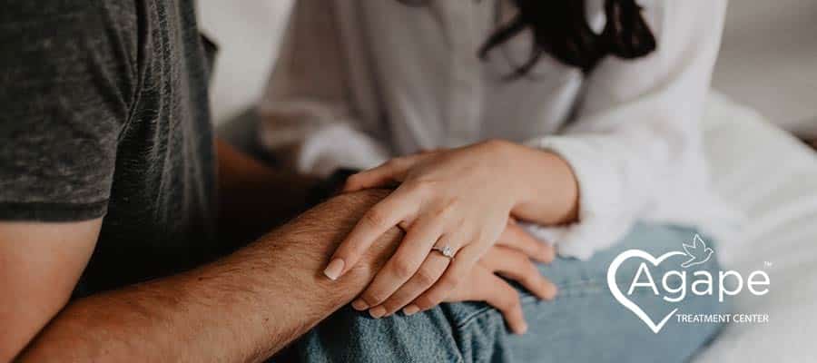 Person holding hands, wearing a white shirt.