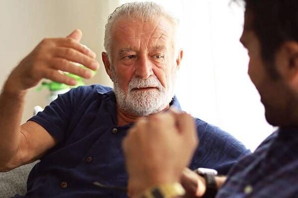 Two people having a conversation, one in a blue shirt gesturing.