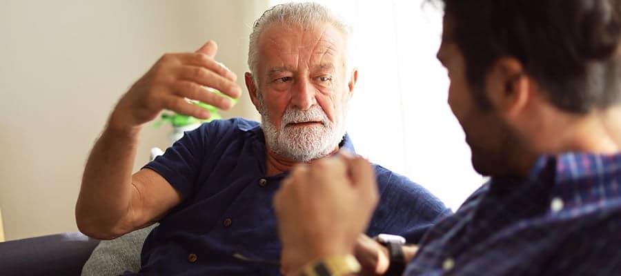 Two people having a conversation, one in a blue shirt gesturing.