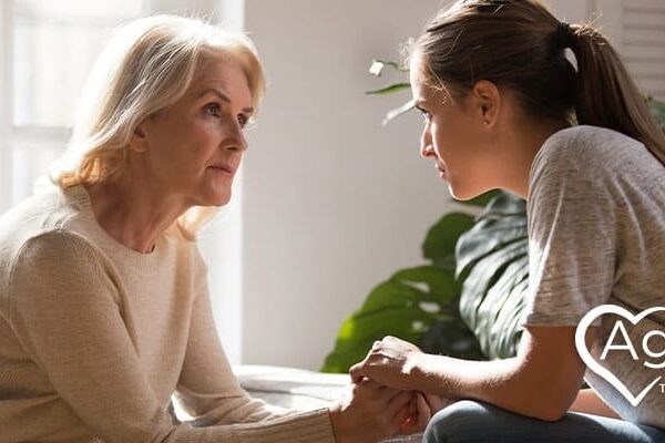 Person in beige sweater looking at woman holding hands.