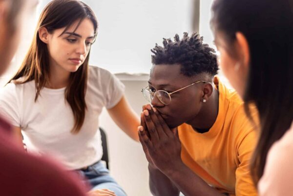 young man looking stressed but surrounded by friends
